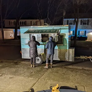 a couple of people standing in front of a food truck