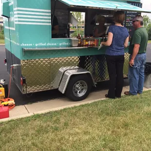 a man and a woman standing in front of a food truck