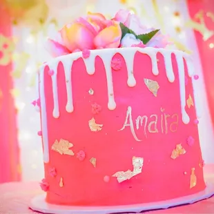 a pink cake with white icing and flowers