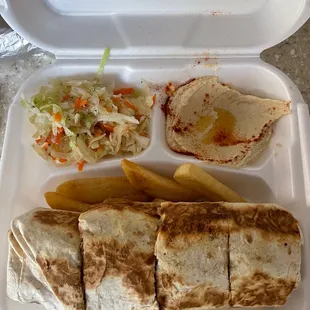 Chicken shawarma sandwich with hummus and salad on a bed of steak fries.