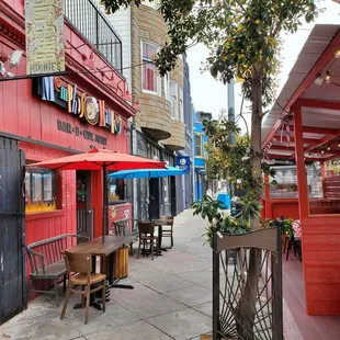 a sidewalk with tables and umbrellas