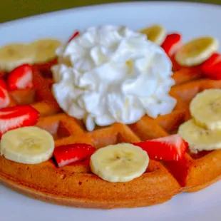 a waffle with strawberries, bananas, and whipped cream