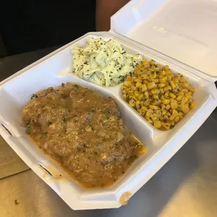 Smothered pork chop with corn and potato salad