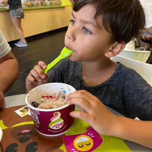 a young boy eating a bowl of ice cream