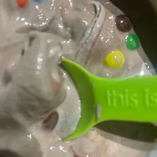 a green spoon in a bowl of ice cream