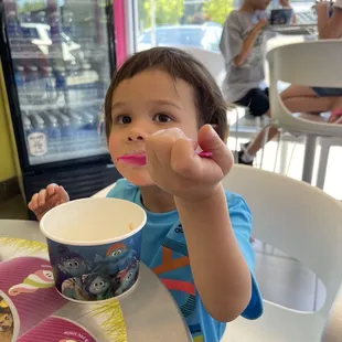 a little boy eating a cup of ice cream