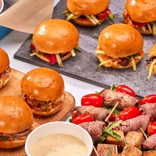 a tray of mini sandwiches with meat skewers