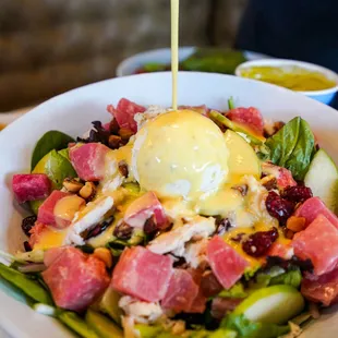 a bowl of salad with dressing being drizzled on top