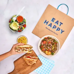 a person holding a sandwich and a bowl of salad