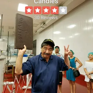 The president of the company holding a lot 10 lb bar of chocolate.