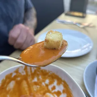a spoon full of soup with a piece of bread on it