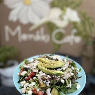 a hand holding a plate of salad