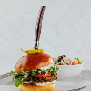 Meráki Steak Burger ( 1/2 lb. Grilled American Wagyu, Red Onion, Tomato, Feta, Arugula, Tzatziki, Brioche Bun)