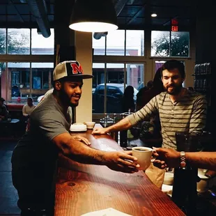 a man handing a cup of coffee