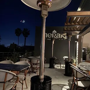 a patio with tables and chairs and a gas heater