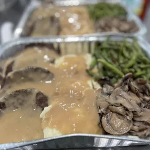 a tray of food with meat and gravy