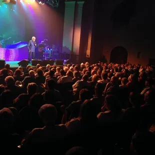 a man on stage with a microphone in front of a crowd