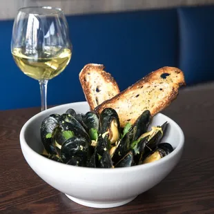 a bowl of mussels and a glass of wine