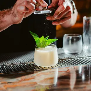 a bartender sprinkling a minty drink
