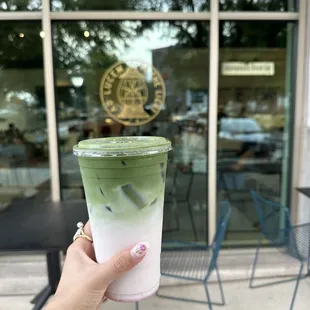 a hand holding a cup of green tea