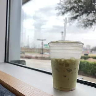 a cup of iced coffee on a window sill