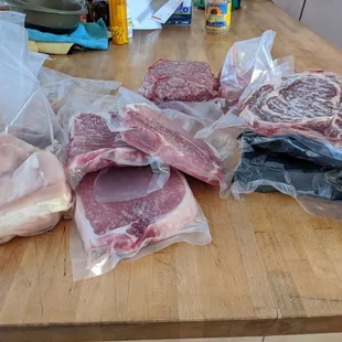 Frozen protein box with t bone steaks, hamburgers, pork chops, bone-in ribeyes, and chicken breast.