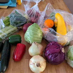 Produce box lots of goodies like peppers, cabbages, onions, cucumbers, fruits, limes, potatoes, and a big bag of chillies.