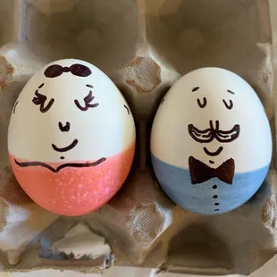 two decorated eggs in a carton
