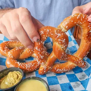 a man holding a pretzel and dipping sauce