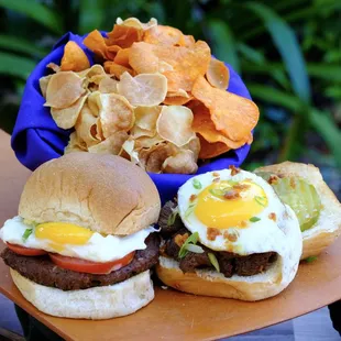 two burgers and chips on a cutting board