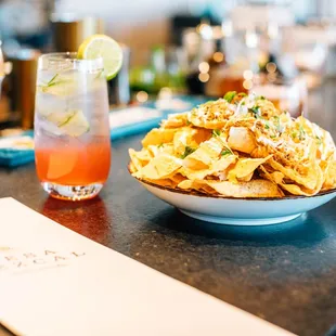 a bowl of nachos and a drink