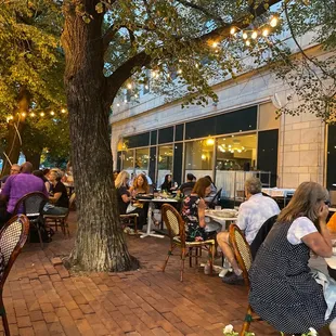 a group of people sitting at tables outside a restaurant