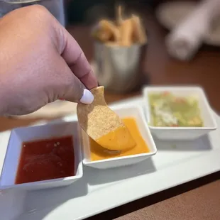a hand dipping a tortilla