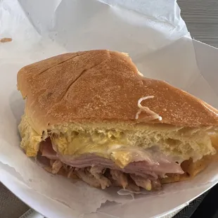 Medianoche =  Seasoned pork, ham, pickles, mustard, mayonnaise and Swiss cheese on medianoche bread
