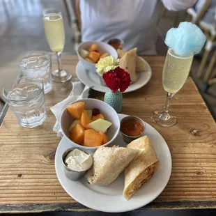 Breakfast Burrito with a side of fruit, Peach Mimosas with blue Cotton Candy on top.