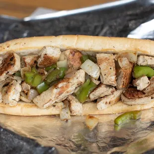 a chicken sandwich with peppers and onions