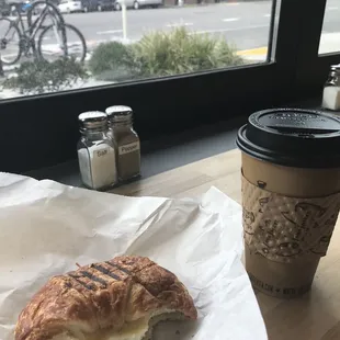 a croissant sandwich and a cup of coffee