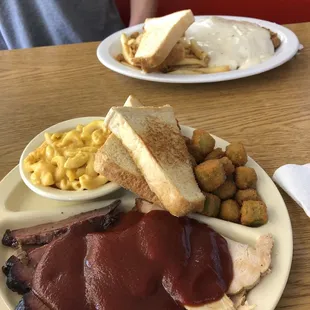 Two meat plate with brisket, turkey, Mac &amp; cheese, and fried okra. Other plate has the chicken fried steak and French fries.