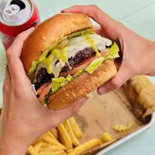 a person holding a hamburger and french fries