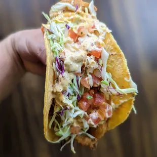 a hand holding a taco