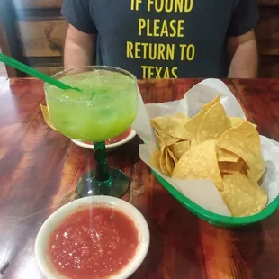 a man sitting at a table with a bowl of chips and a bowl of guacamole
