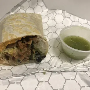 Half of an al pastor burrito with side of salsa