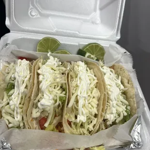 Shrimp tacos topped with lettuce, cheese, sour cream, and tomatoes.