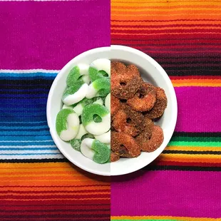 a bowl of sugared donuts on a colorful table cloth
