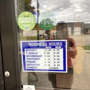 a business hours sign in the window