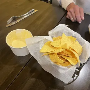 a person sitting at a table with a basket of tortillas and a bowl of quesadilla