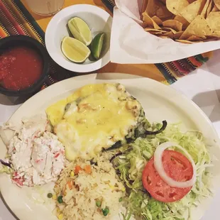 Seafood chile relleno, small crab salad, rice and another small salad consisting of iceberg lettuce and a tomato