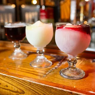 three different drinks on a bar