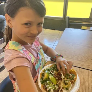 a young girl holding a plate of food