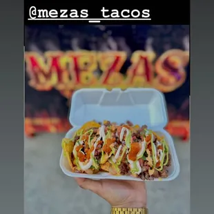 a hand holding a container of tacoss